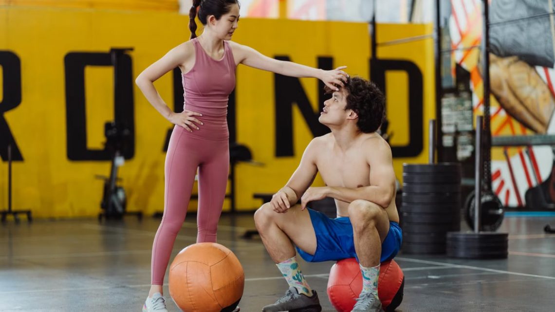 A couple sharing a moment in a gym setting with medicine balls, expressing fitness and togetherness.