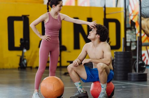 A couple sharing a moment in a gym setting with medicine balls, expressing fitness and togetherness.